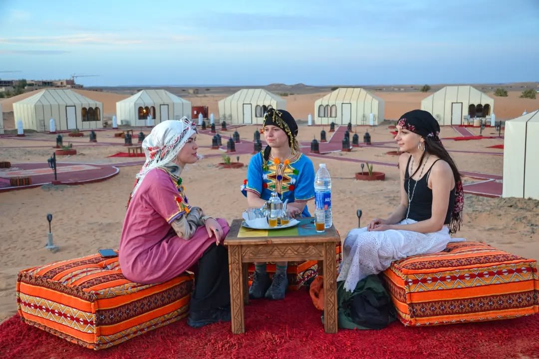 Guests relaxing with Moroccan tea in the outdoor camp lounge